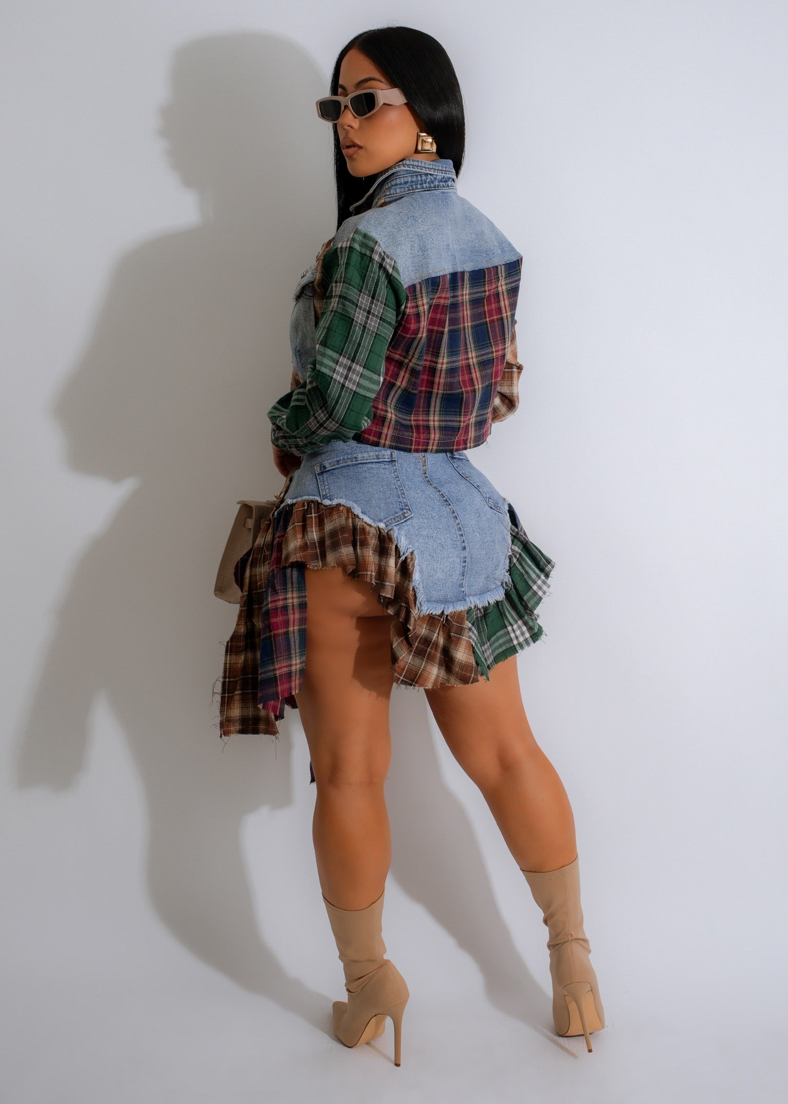 Cropped tailored button down jacket with a mix of denim and patchwork tartan print, with matching asymmetrical denim skirt features plaid ruffle accents and a tie-waist belt