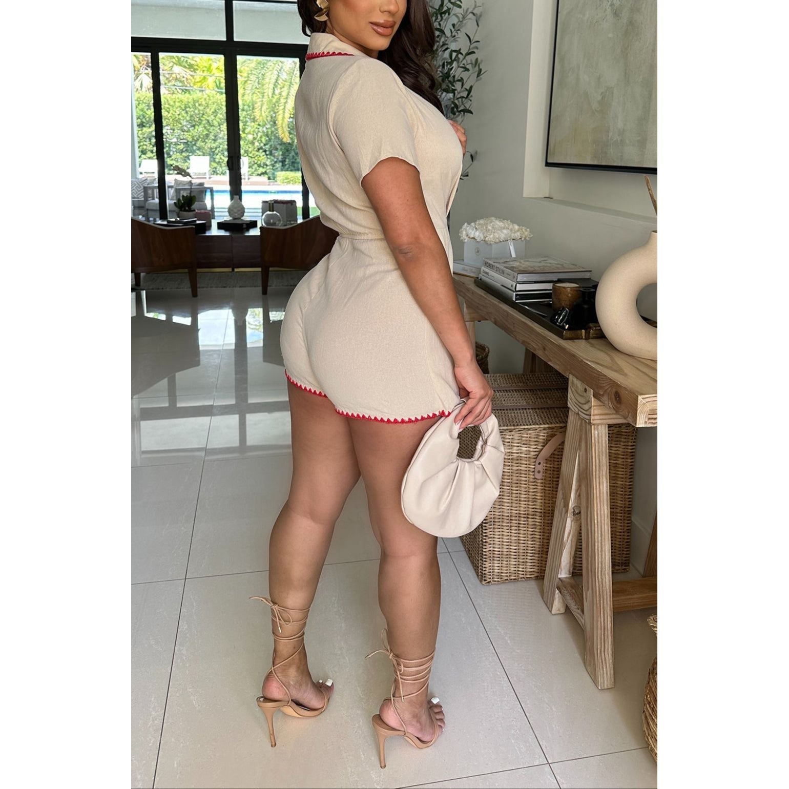 WOMAN IN SHORT SLEEVE BEIGE WRAP STYLE ROMPER WITH RED CROCHET HEM 