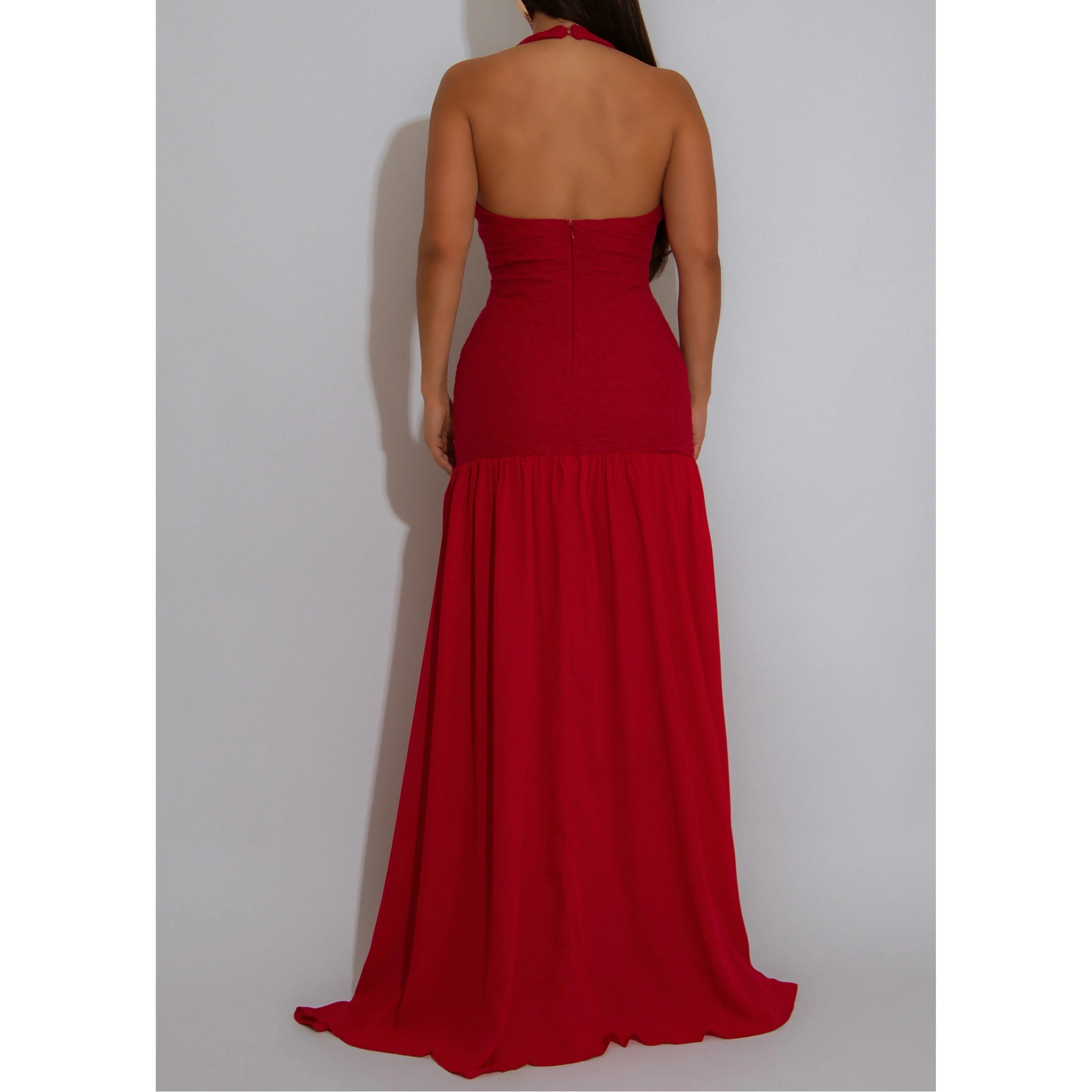Woman wearing a red ruched halter neck gown with gold embellishment by the bust area and chiffon style maxi skirt 