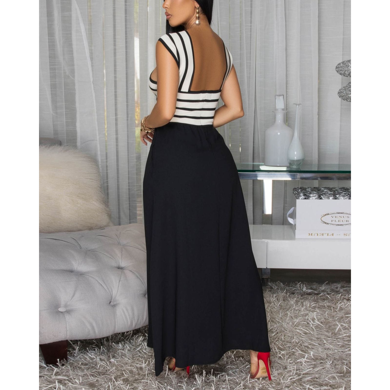 Woman wearing sleeveless knit bodice maxi dress featuring a refined halter neckline and striking striped bodice, a playful flowy black skirt w/ side pockets .