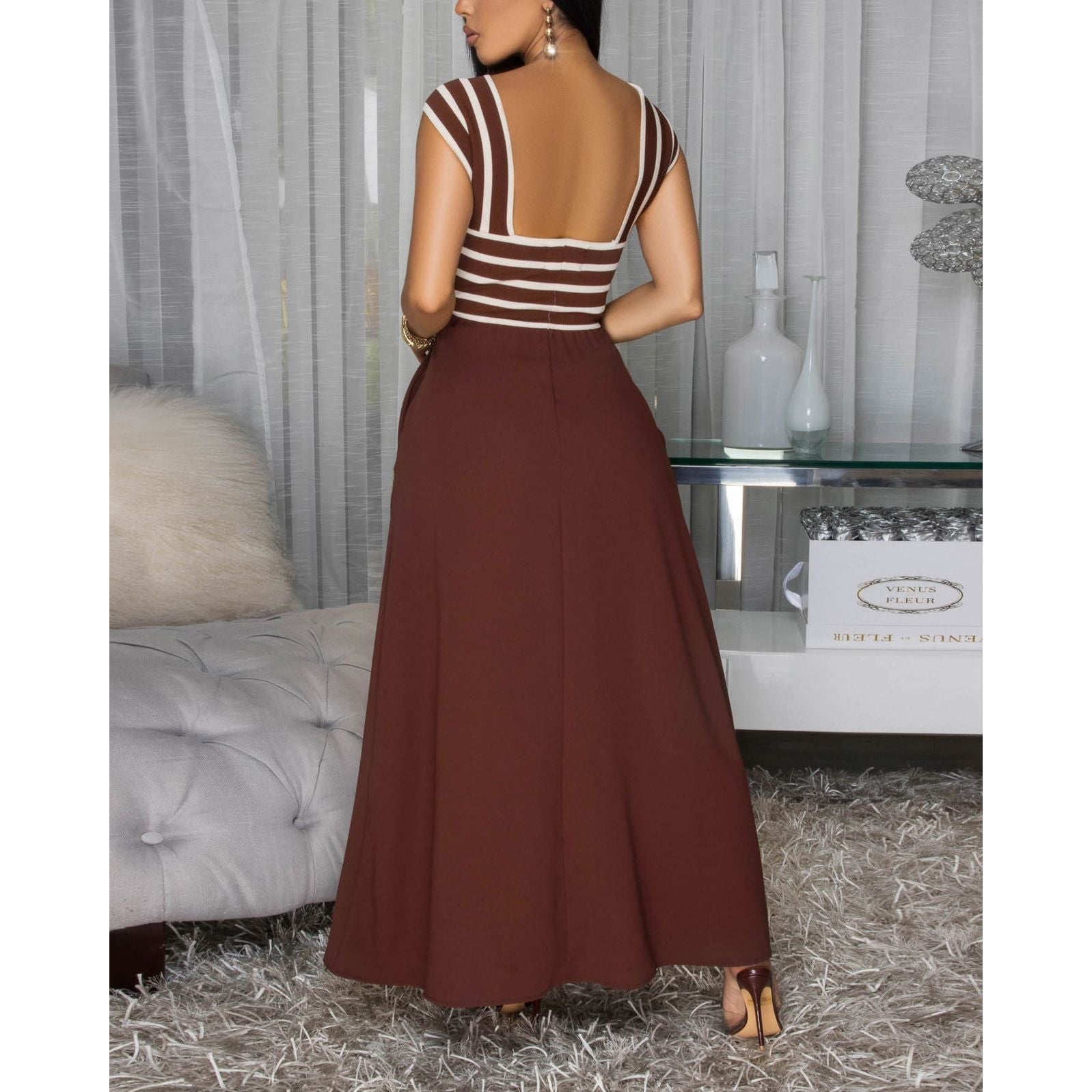 Woman wearing sleeveless knit bodice maxi dress featuring a refined halter neckline and striking brown and cream striped bodice, a playful flowy black skirt w/ side pockets .