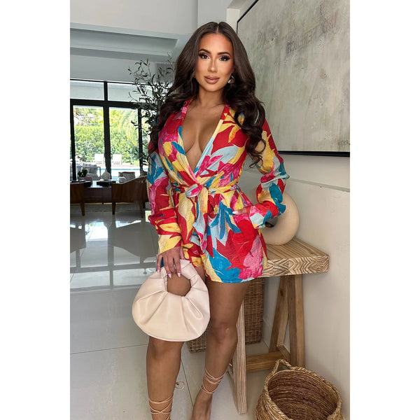 Red vibrant floral pattern romper with long sleeves, v-cut neckline and adjustable tie waist .